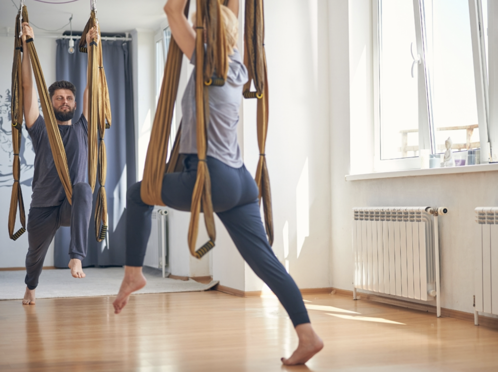 Selbständiger Yogalehrer, der eine Aerial Yoga Stunde unterrichtet