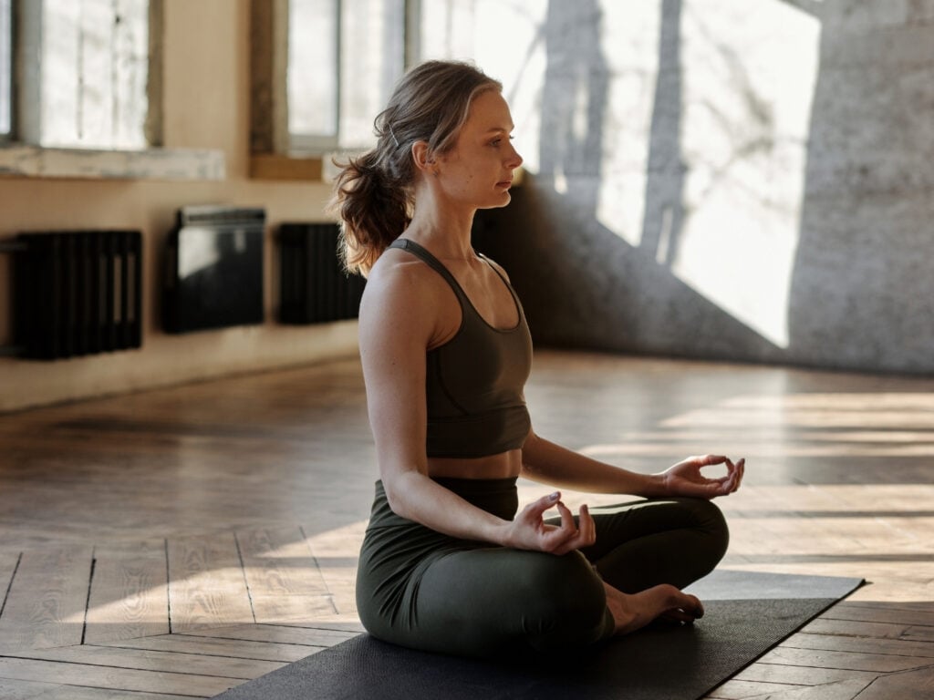 Yogalehrerin beim Meditieren und Eröffnen ihrer Stunde