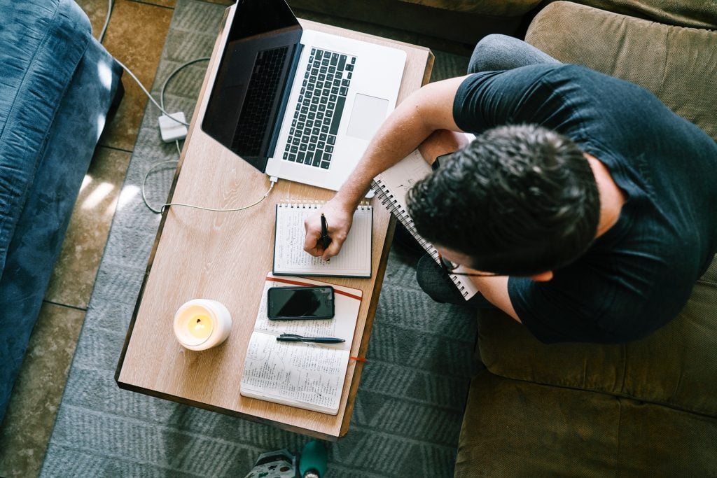 Mann arbeitet am Laptop und macht sich Notizen