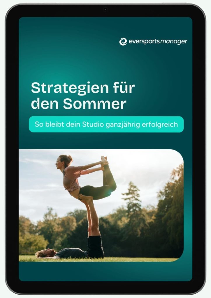 Ein Paar macht Acro Yoga auf einer Wiese in der Natur, die Sonne scheint und Bäume umgeben sie.