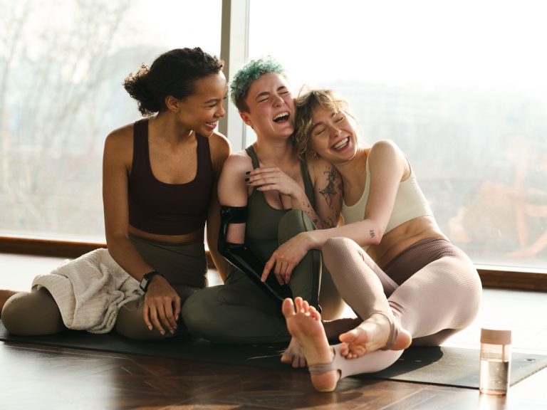 Frauen sitzen auf Yogamatte und haben spass | yoga report