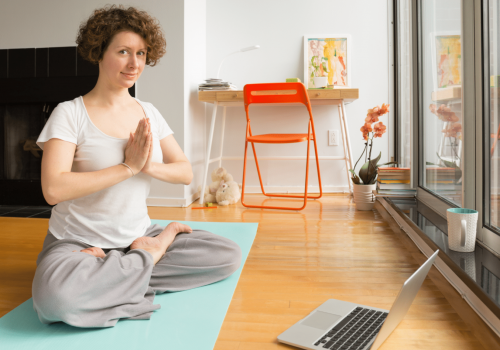 Vrouw doet yogapose thuis tijdens online les